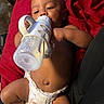 Tyrone is registered to the contest to win money with this photo: baby, bottle, diaper, infant, hand, lying_down, red_blanket, cute, feeding, child, skin, indoors, relaxed, peaceful, portrait, baby_bottle, newborn, small_child, human, closeup