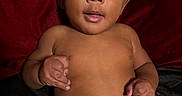 Tyrone joined the competition — help win amazing prizes! baby, infant, diaper, bare_chest, wide_eyes, curious_expression, lying_down, red_blanket, black_blanket, skin, cute, child, portrait, indoors, one_person, young_child, human, face, hands, looking_up