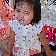 Mina joined the competition — help win amazing prizes! animal_print, carpet, casual, chair, child, cute, dress, floor, girl, hair_tie, happy, indoor, patterned_clothing, play_area, safety_gate, sitting, smiling, toddler, toy, young_child