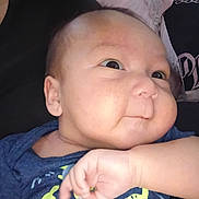 Royal is registered to the contest to win money with this photo: baby, infant, child, face, cheeks, blue_shirt, dinosaur_print, hand, curious, portrait, closeup, skin, cute, resting, expression, young, person, indoors, clothing, smile