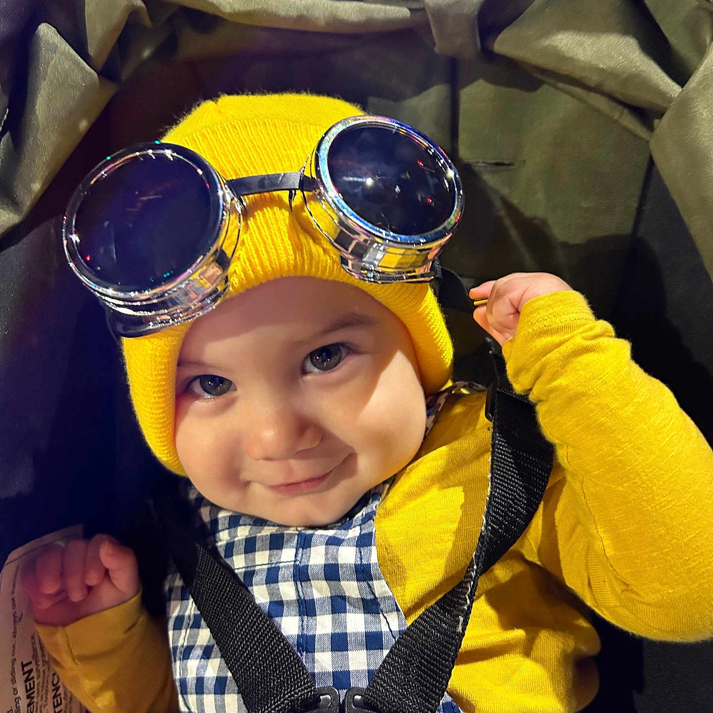 Isaiah Mendez joined the competition — help win amazing prizes! baby, babywearing, beanie, black_straps, checkered_clothing, child, childwear, closeup, cute, face, goggles, happy, harness, indoor, infant, person, portrait, smiling, stroller, yellow_hat
