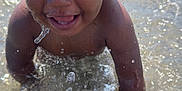 Aaron participe au concours pour gagner de l'argent avec cette photo : toddler, child, water, splash, beach, hat, bucket_hat, happy, smiling, sunlight, outdoor, summer, play, fun, wet, person, face, ocean, sand, recreation