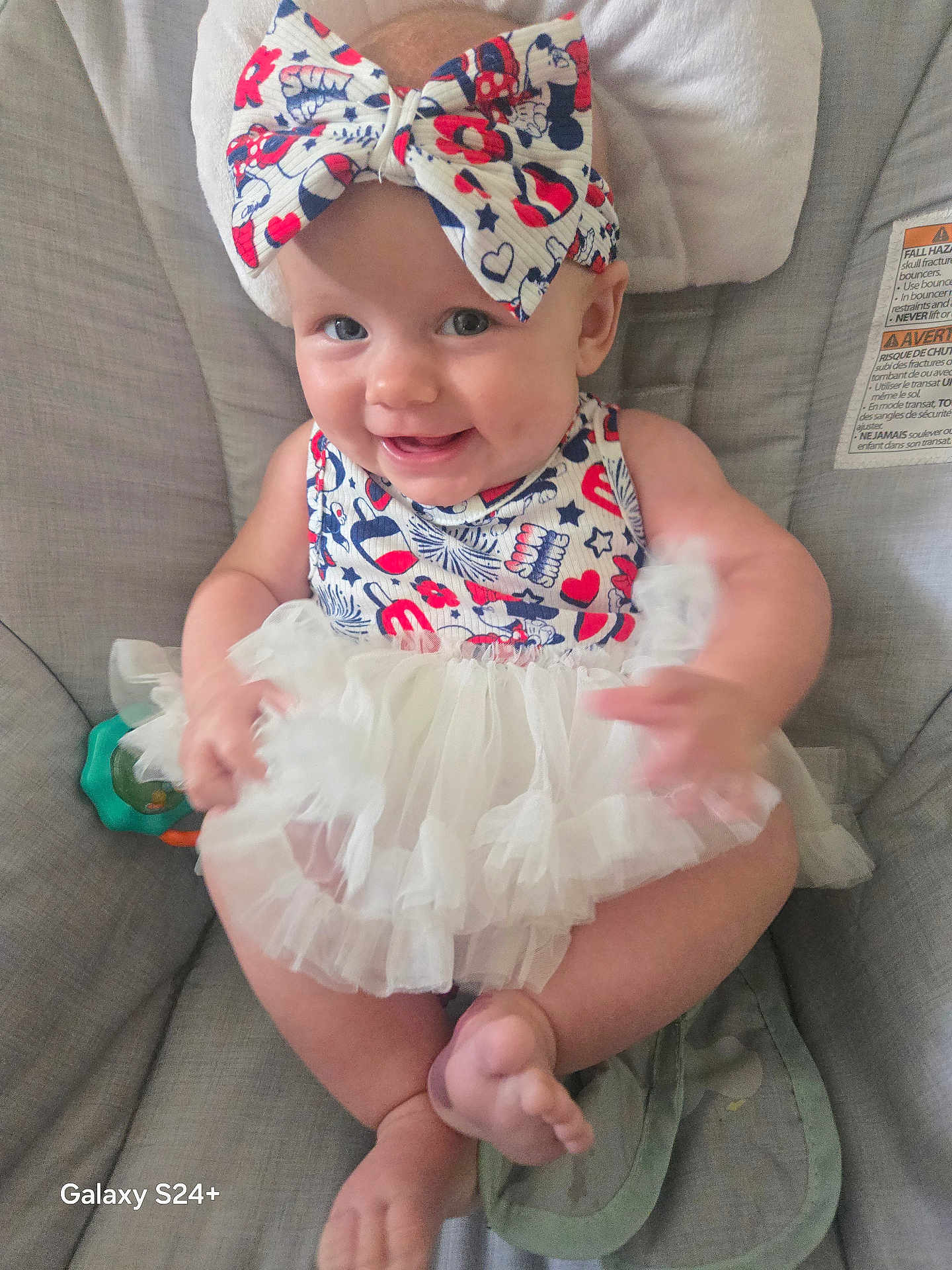 Juni is registered to the contest to win money with this photo: baby, child, smiling, bow, headband, dress, tulle_skirt, sitting, chair, cushion, cute, happy, indoor, person, infant, skin, foot, hand, face, dimples