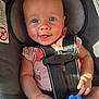baby, blue_eyes, car_seat, child, closeup, cute, face, hand, happy, indoor, infant, person, pink_clothing, portrait, safety_harness, seat, seatbelt, smiling, sunlight, toy