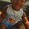 toddler, smiling, child, sitting, car_interior, tank_top, shorts, sneakers, socks, gold_chain, cute, happy, portrait, baby, indoors, seat, clothing, footwear, person, sunlight