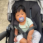 Jamphel joined the competition — help win amazing prizes! baby, stroller, pacifier, child, infant, outdoor, sidewalk, curious, black_stroller, casual_clothing, foot, holding, person, young_child, baby_clothes, daylight, urban, comfort, seated, transportation