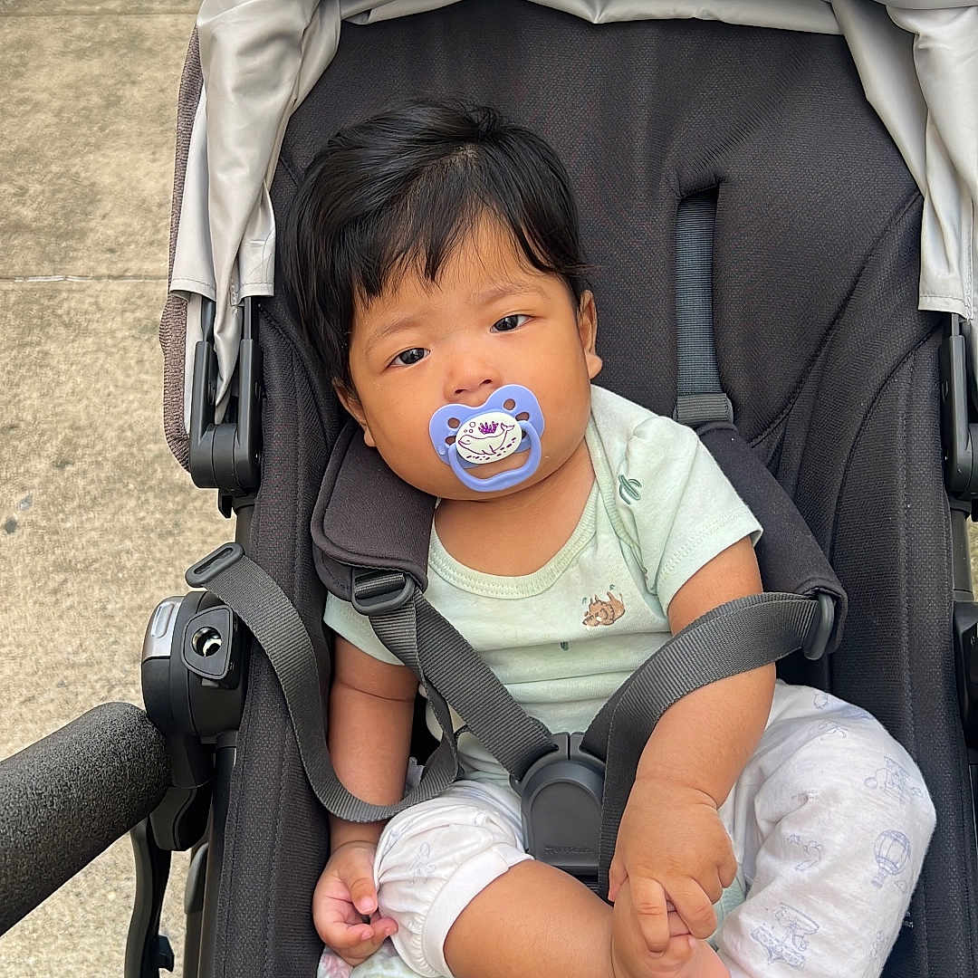 Jamphel joined the competition — help win amazing prizes! baby, stroller, pacifier, child, infant, outdoor, sidewalk, curious, black_stroller, casual_clothing, foot, holding, person, young_child, baby_clothes, daylight, urban, comfort, seated, transportation
