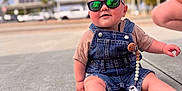 Jameson joined the competition — help win amazing prizes! baby, child, sunglasses, denim_overalls, pacifier, outdoor, sidewalk, sunny, smiling, cute, infant, reflection, clothing, casual, person, legs, hand, accessory, urban, daytime