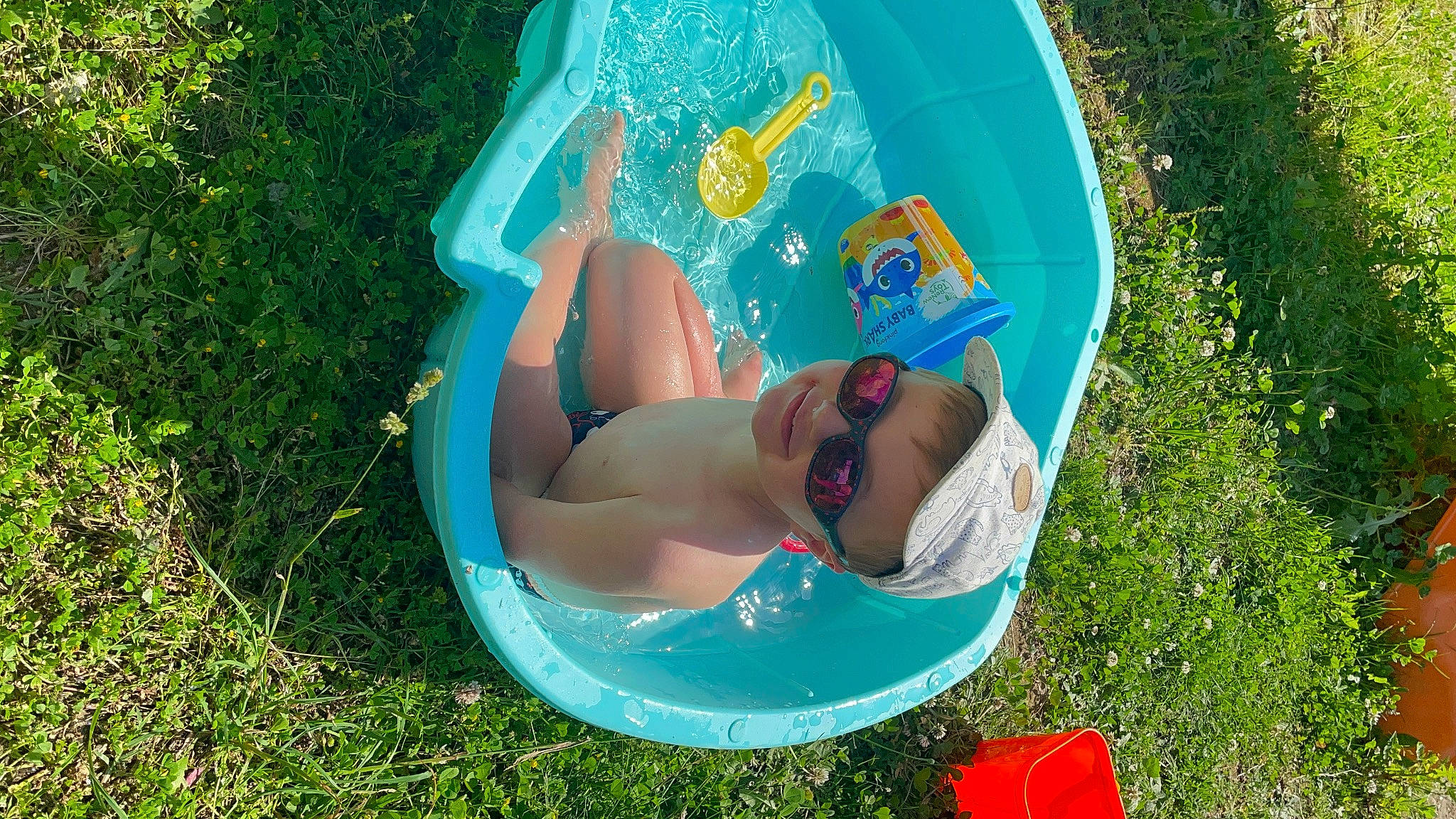 Basile a rejoint le concours — aidez-le/la à gagner de superbes lots ! azure, bathing, child, electric_blue, eyewear, fun, grass, green, happy, joy, lawn, leisure, people_in_nature, person, personal_protective_equipment, plant, recreation, sitting, sunglasses, sunlight