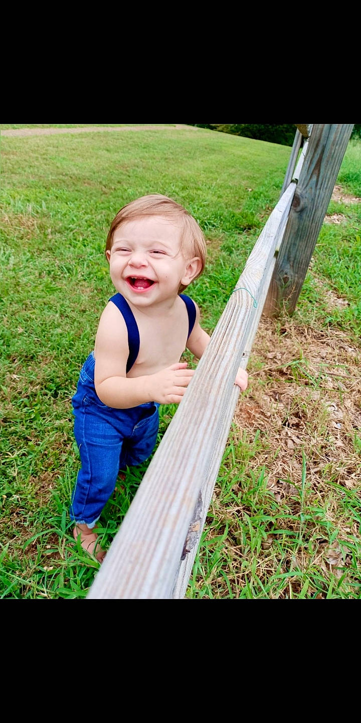 Henry is registered to the contest to win money with this photo: arm, baby, baby_toddler_clothing, face, fun, grass, grass_family, hand, happy, human_body, joy, lawn, leaf, leisure, meadow, people_in_nature, person, plant, smile, toddler