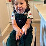 Osmar joined the competition — help win amazing prizes! child, toddler, smiling, curly_hair, green_overalls, kitchen, stool, clapping, happy, indoor, person, cabinet, countertop, appliance, cupboard, floor, shirt, toy_truck_pattern, furniture, light