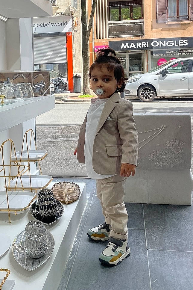 Amir participe au concours pour gagner de l'argent avec cette photo : building, car, chair, child, fashion_design, flooring, outdoor_shoe, person, plate, shoe, smile, sneakers, standing, table, tableware, tire, toddler, vehicle, wheel, white