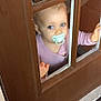 baby, child, pacifier, door, window, glass, blue_eyes, pink_clothing, hand, curiosity, indoor, threshold, door_frame, reflection, looking_up, portrait, mat, wood, cute, smile