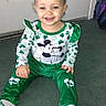 toddler, child, smiling, green_clothing, mickey_mouse, pigtails, carpet, indoor, door, happy, sitting, sock, cute, person, baby, playful, portrait, household, young_child, fun