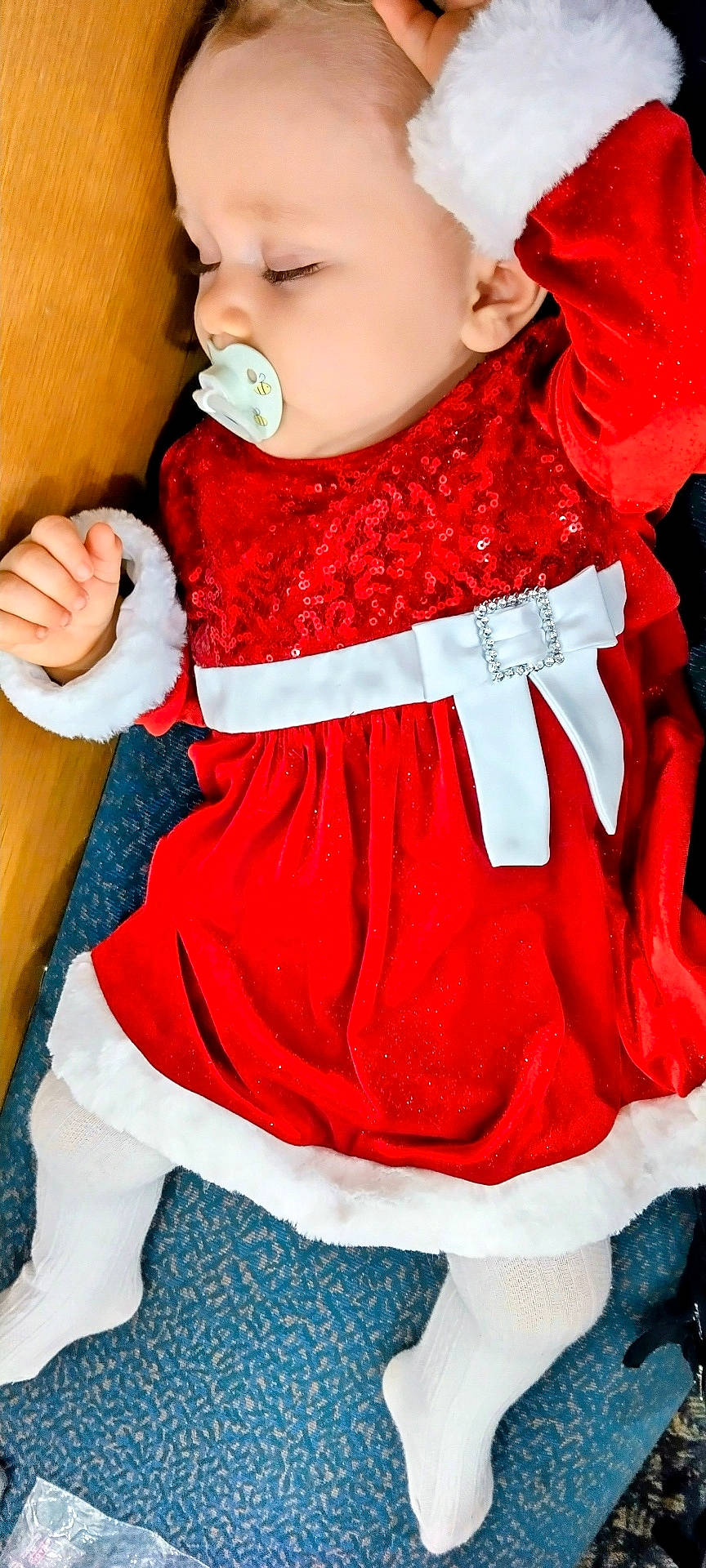 Savannah joined the competition — help win amazing prizes! baby, buckle, closed_eyes, fabric, face, festive, fur_trim, hand, holiday_outfit, infant, legs, pacifier, portrait, red_dress, santa_dress, sequins, sleeping_baby, stockings, white_belt, wooden_surface
