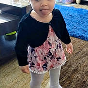 Savannah is registered to the contest to win money with this photo: child, toddler, headband, sticking_out_tongue, floral_dress, cardigan, tights, socks, standing, rug, carpet, toys, stuffed_animal, living_room, playmat, portrait, indoor, cute_expression, blonde_hair, floor