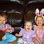 child, baby, toddler, smiling, sitting, bunny_ears, plush_toy, colorful_clothing, happy, indoor, carpet, leather_couch, portrait, cute, easter, family, celebration, playful, blue_eyes, pink_dress