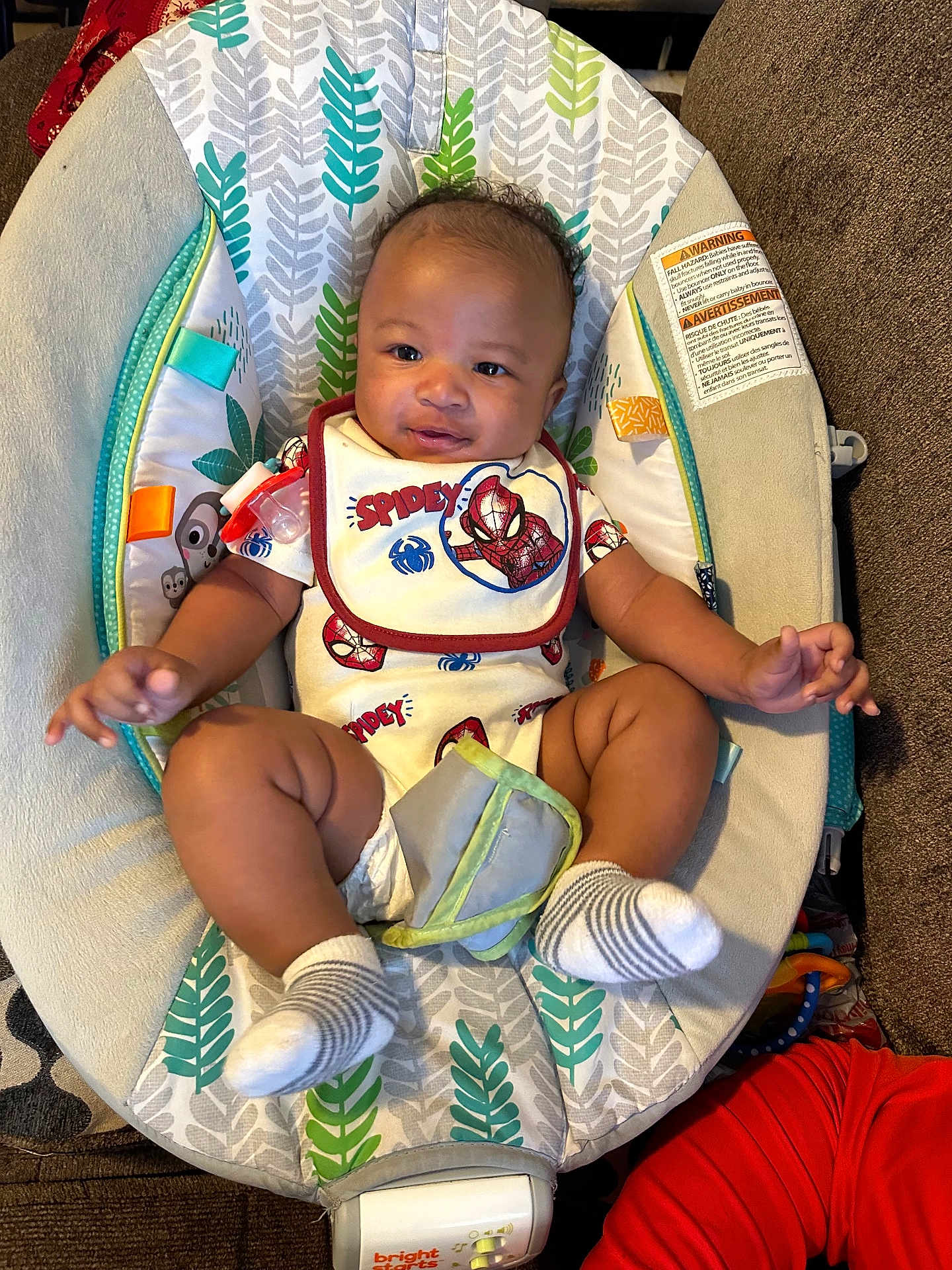 Javonte is registered to the contest to win money with this photo: baby, infant, child, spiderman_outfit, bib, baby_seat, leaf_pattern, socks, indoor, couch, cushion, smiling, happy, person, portrait, toddler, clothing, furniture, home, cute