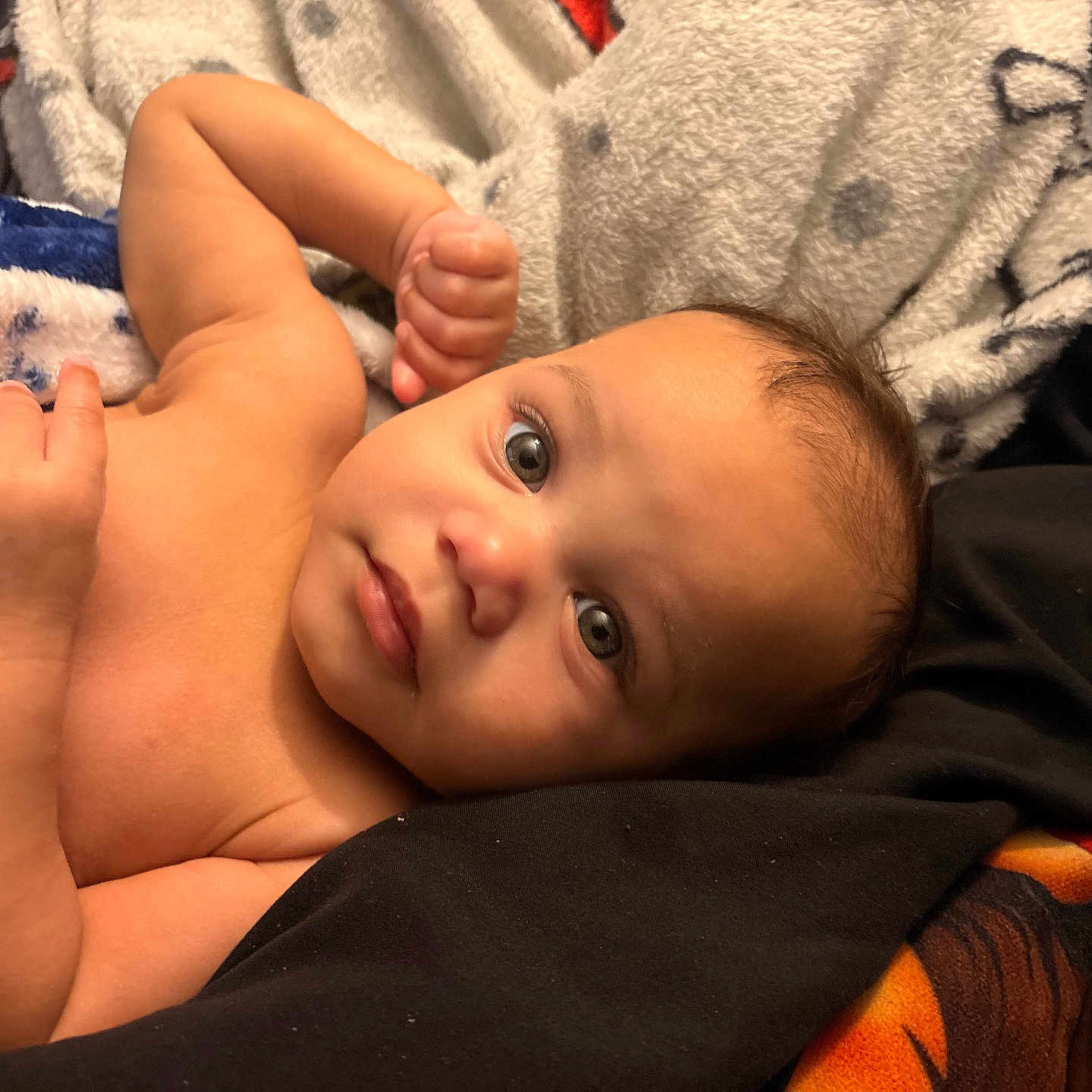 Kamarion is registered to the contest to win money with this photo: baby, infant, blanket, skin, face, eyes, arm, hand, lying_down, cozy, soft, cute, curious, indoors, child, newborn, expression, resting, portrait, toddler