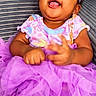baby, child, toddler, purple_tutu, headband, smiling, happy, clothing, cute, portrait, indoor, couch, seated, infant, skin, hands, face, expression, playful, colorful