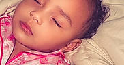 Ayla is registered to the contest to win money with this photo: child, sleeping, pajamas, bed, blanket, curly_hair, face, peaceful, indoors, soft_lighting, pink_clothing, person, toddler, resting, cute, baby, portrait, sleep, relaxation, cozy