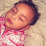 child, sleeping, pajamas, bed, blanket, curly_hair, face, peaceful, indoors, soft_lighting, pink_clothing, person, toddler, resting, cute, baby, portrait, sleep, relaxation, cozy