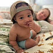 Jackson joined the competition — help win amazing prizes! toddler, child, baby, cap, bed, sheet, cheetah_print, hand, face, smile, adult, blurred_background, indoor, person, curious, skin, furniture, casual, resting, home