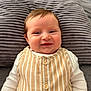 Elizabeth is registered to the contest to win money with this photo: baby, smiling, face, infant, pillow, striped_clothing, white_sleeves, cute, happy, child, young, indoors, portrait, closeup, skin, head, eyes, mouth, human, lying_down