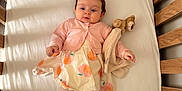 Elizabeth is registered to the contest to win money with this photo: baby, crib, wooden_crib, toddler, dress, cardigan, tights, toy, stuffed_animal, blanket, indoor, sunlight, shadow, sleeping_area, child, cute, infant, person, soft_toy, relaxing
