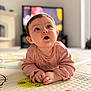 Elizabeth is registered to the contest to win money with this photo: baby, infant, child, playmat, curious, indoors, living_room, floor, clothing, long_sleeve, face, hands, expression, couch, television, clock, soft_lighting, colorful, young, portrait