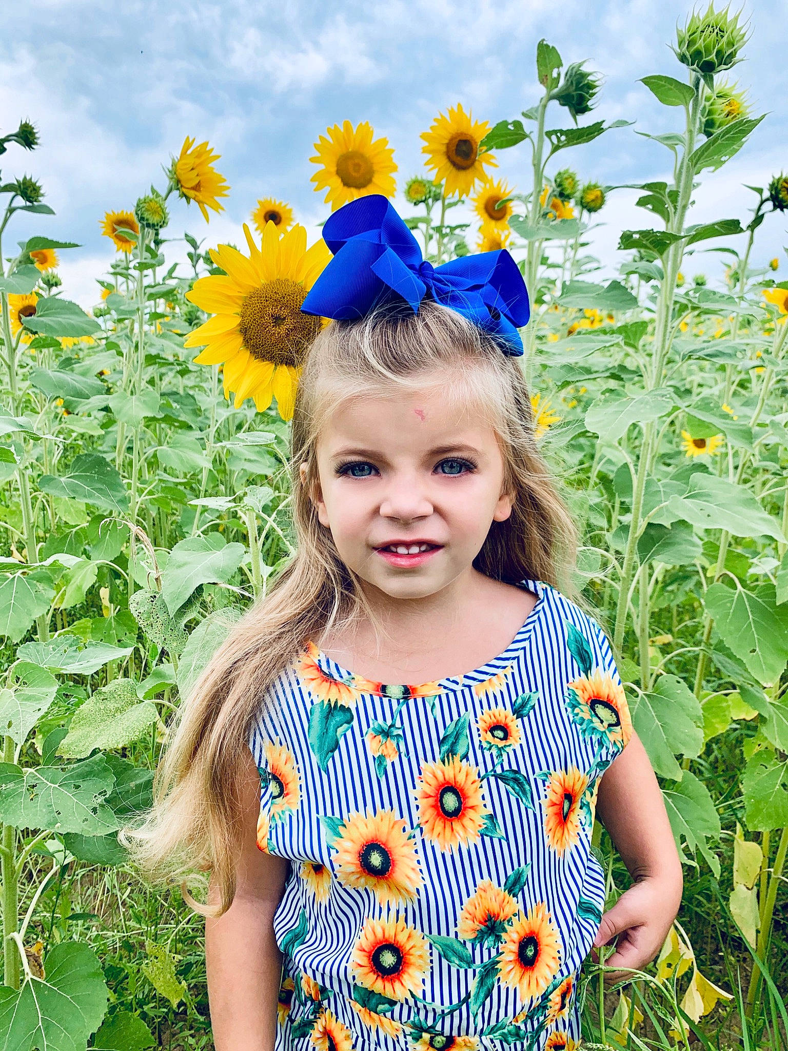 Kora is registered to the contest to win money with this photo: child, fawn, flower, flowering_plant, happy, people_in_nature, person, plant, smile, summer, sunflower, toddler, vegetarian_food, wildflower, yellow