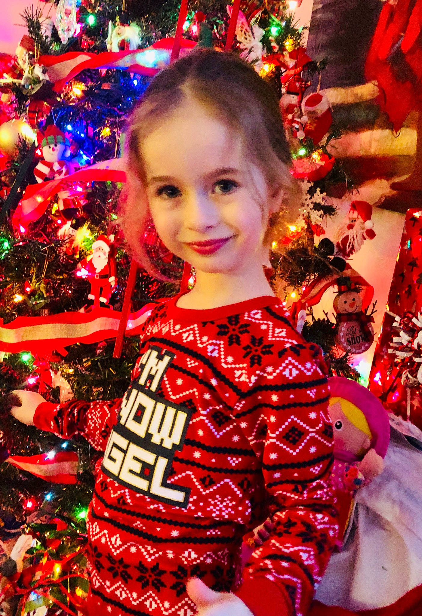 Jade a rejoint le concours — aidez-le/la à gagner de superbes lots ! christmas_decoration, christmas_eve, christmas_ornament, christmas_tree, event, facial_expression, fun, happy, head, holiday, holiday_ornament, joy, light, ornament, person, red, sleeve, smile, standing, toddler