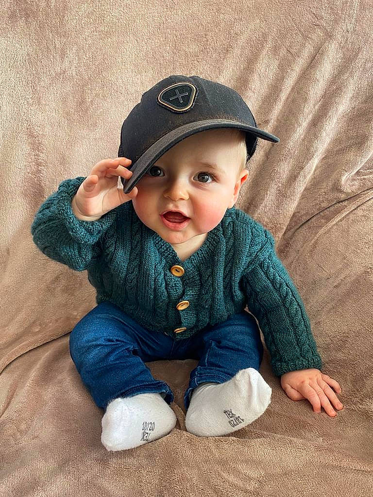Liam a rejoint le concours — aidez-le/la à gagner de superbes lots ! baby, baby_toddler_clothing, baseball_cap, cap, cheek, collar, electric_blue, eye, fashion_accessory, flash_photography, grass, happy, hat, head, headwear, pattern, person, portrait_photography, sitting, sleeve