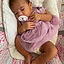 Alaska joined the competition — help win amazing prizes! baby, sleeping, pacifier, purple_dress, tutu, infant, cushion, baby_seat, patterned_fabric, hands, feet, cute, peaceful, child, indoors, soft_lighting, skin, relaxation, comfort, closeup