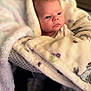 baby, blanket, infant, face, feet, cozy, patterned_blanket, indoor, child, wrapped, cute, newborn, soft_texture, warm, portrait, person, laying, expression, young, comfort
