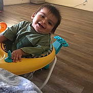 Moon joined the competition — help win amazing prizes! toddler, baby_walker, child, smiling, indoor, floor, wooden_floor, toy, clothing, green_shirt, face, happy, person, young_child, playful, home, room, electric_outlet, wall, cable