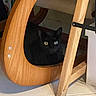 black_cat, cat, animal, pet, feline, glowing_eyes, sitting, hiding, wooden_chair, furniture, indoor, home, floor, tile_floor, wood, chair_leg, shadow, portrait, curious, funny