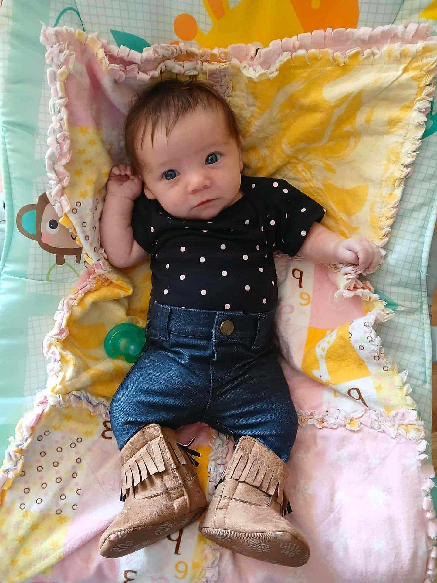 Brooklynn is registered to the contest to win money with this photo: baby, infant, blanket, clothing, denim, boots, polka_dot, fringe, pacifier, pattern, cute, child, portrait, laying_down, indoor, fabric, colorful, soft, small, person