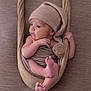 baby, newborn, infant, wrapped, knit_hat, pom_pom, fabric, hammock, beige, neutral_background, cute, peaceful, resting, soft_texture, portrait, small_feet, tiny_hands, child, indoors, cozy