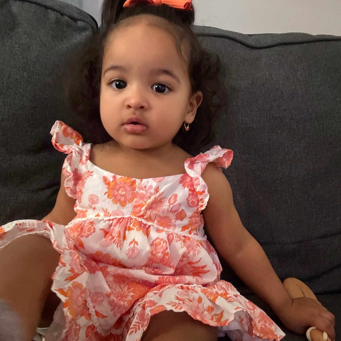 Camila joined the competition — help win amazing prizes! bow, casual_clothing, child, couch, curious, dress, earrings, floral_pattern, furniture, girl, hair, home, indoor, portrait, sitting, sofa, toddler, toy, wooden_toy, young_child