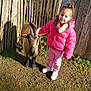 Mia participe au concours pour gagner de l'argent avec cette photo : child, girl, goat, animal, outdoor, fence, wood, sunlight, grass, dirt, jacket, pink_clothing, shoes, smile, petting, nature, daylight, young, casual, happy