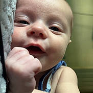 Oaklynn is registered to the contest to win money with this photo: baby, infant, face, hand, skin, expression, cute, portrait, child, closeup, soft, lying, fist, curious, eyes, cheeks, indoor, person, young, smile