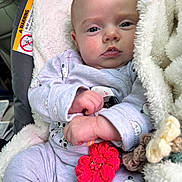 Charika joined the competition — help win amazing prizes! baby, infant, pajamas, blanket, car_seat, face, drool, toy, crochet, flower, hand, soft_texture, clothing, person, portrait, indoor, cute, expression, comfort, child