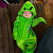 Kenzie is registered to the contest to win money with this photo: baby, sleeping, costume, green, monster, blanket, dog, pet, floor, wooden_floor, indoors, cute, child, cozy, animal, resting, soft, fabric, clothing, nap
