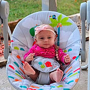 Evelyn is registered to the contest to win money with this photo: baby, infant, swing, outdoor, headband, pink_clothing, foot, baby_seat, colorful, playful, grass, concrete, toy, nature, child, seat_belt, cute, person, portrait, baby_toy