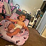 baby, candid, carpet, child, child_furniture, curtain, diaper, household_items, indoor, living_room, minnie_mouse, pacifier, plastic_packaging, play_slide, purple_chair, relaxed, toddler, toys, vacuum_cleaner, window