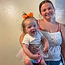 baby, casual_clothing, child, family, fun, happy, holding, home, indoor, jeans, joy, motion_blur, orange_bow, person, portrait, smile, toddler, white_top, woman, young_adult