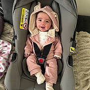 Ava joined the competition — help win amazing prizes! baby, blanket, car_seat, child, comfort, cozy, cute, fabric, footwear, happy, hooded_jacket, indoors, infant, person, pink_clothing, seatbelt, sitting, smiling, soft_texture, white_socks