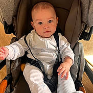 Anthony is registered to the contest to win money with this photo: baby, infant, stroller, child, onesie, seatbelt, straps, sitting, cute, indoors, person, face, hand, footwear, clothing, wooden_handle, expression, looking, young, portrait
