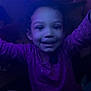 Legacy is registered to the contest to win money with this photo: child, smiling, purple_clothing, polka_dot, face, indoor, glowing_light, colorful_lights, curly_hair, happy, playful, dark_background, earrings, sitting, toy, cute, young_child, portrait, nighttime, fun